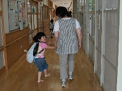 先生と手をつないで廊下を歩く子ども